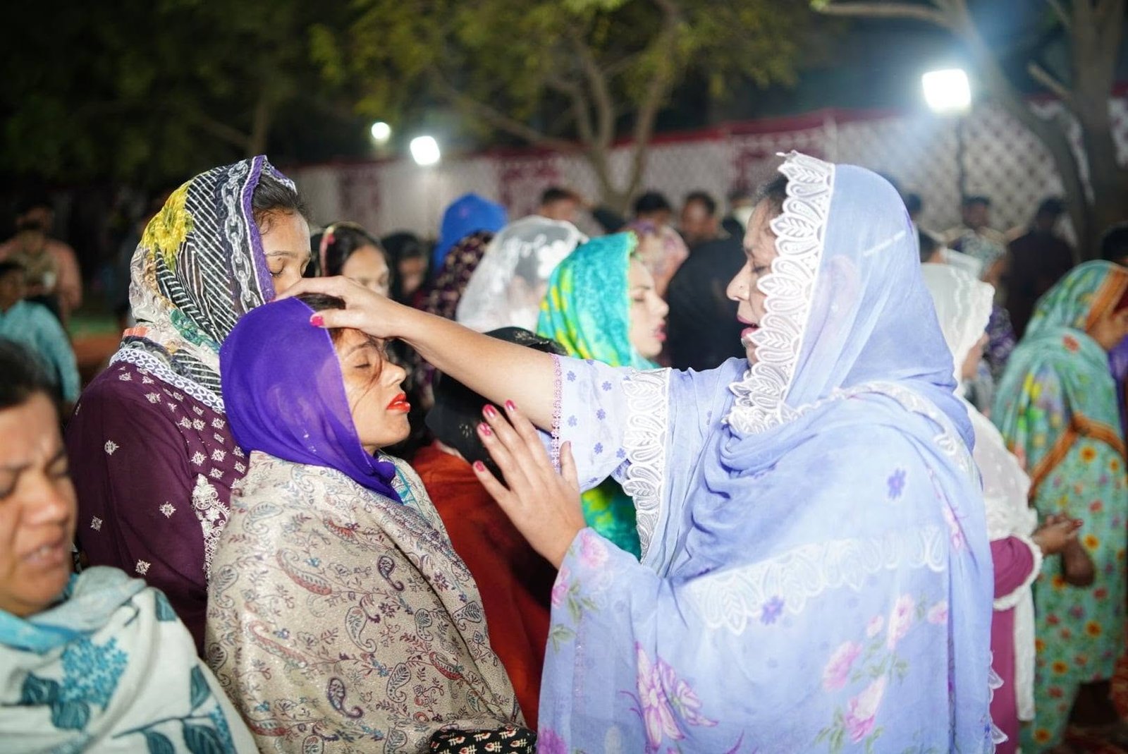 Praying over a woman during an outdoor gathering